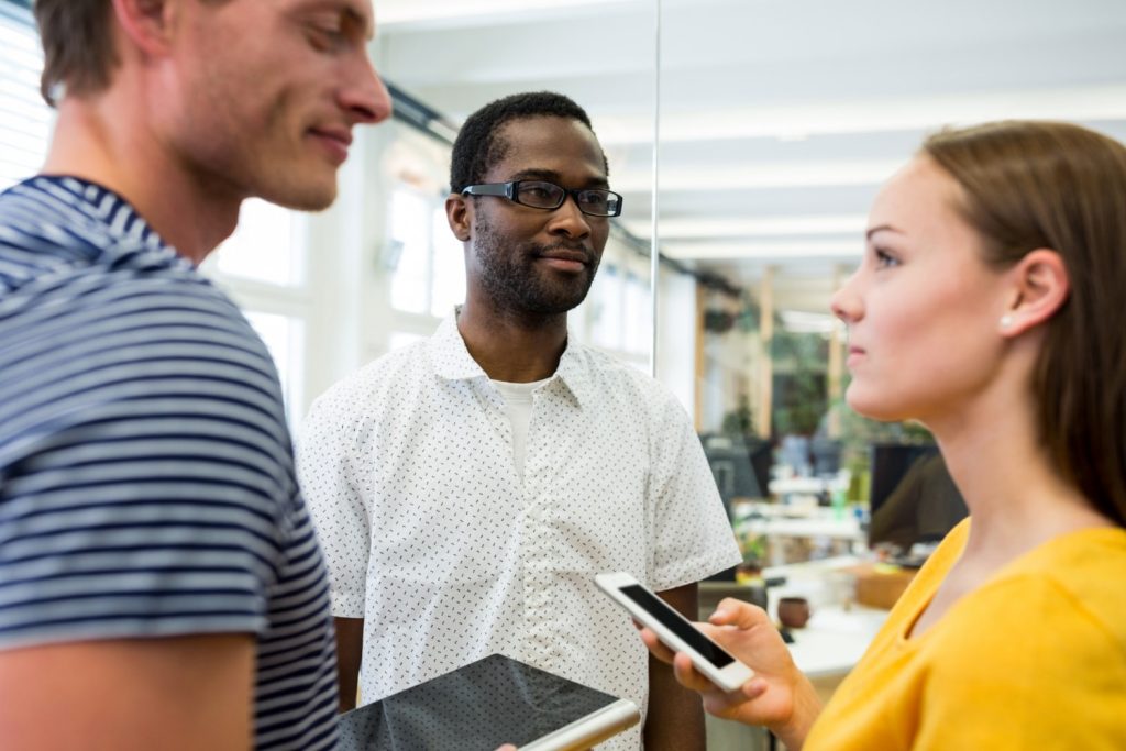 Current image: A group of professionals engages in a discussion in a modern office space, leveraging seamless communication tools for effective collaboration. One individual holds a smartphone, enhancing unified communications and team productivity in a business telecom solutions environment.